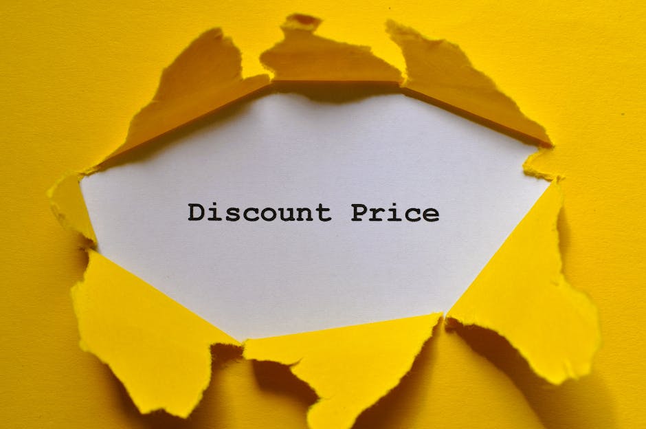 A close-up of a torn yellow paper sheet revealing a white inner layer with the words 'Discount Price' written in bold, black typewriter-style font. The torn edges of the yellow paper are irregular and